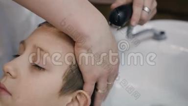 特写镜头。 发型师在美容院或理发店里给年轻人洗头发。 理发师男士洗头